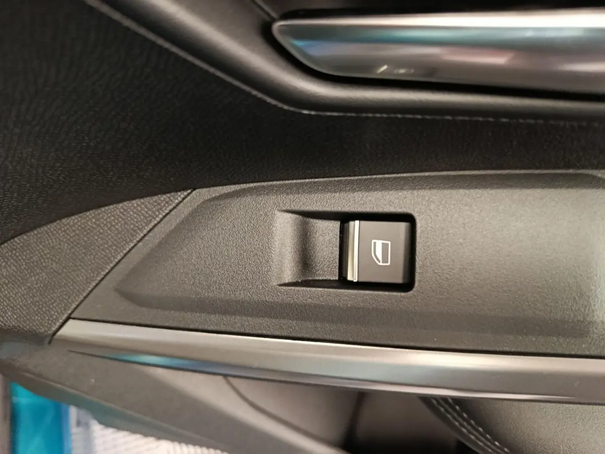 Gros plan sur le bouton de commande de vitre électrique côté conducteur du Peugeot 3008 bleu 2025.