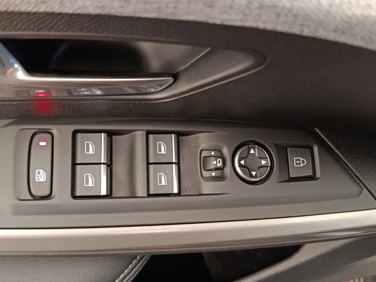 Vue rapprochée des commandes de lève-vitres et rétroviseurs sur la porte côté gauche d’un Peugeot 3008 bleu 2025.