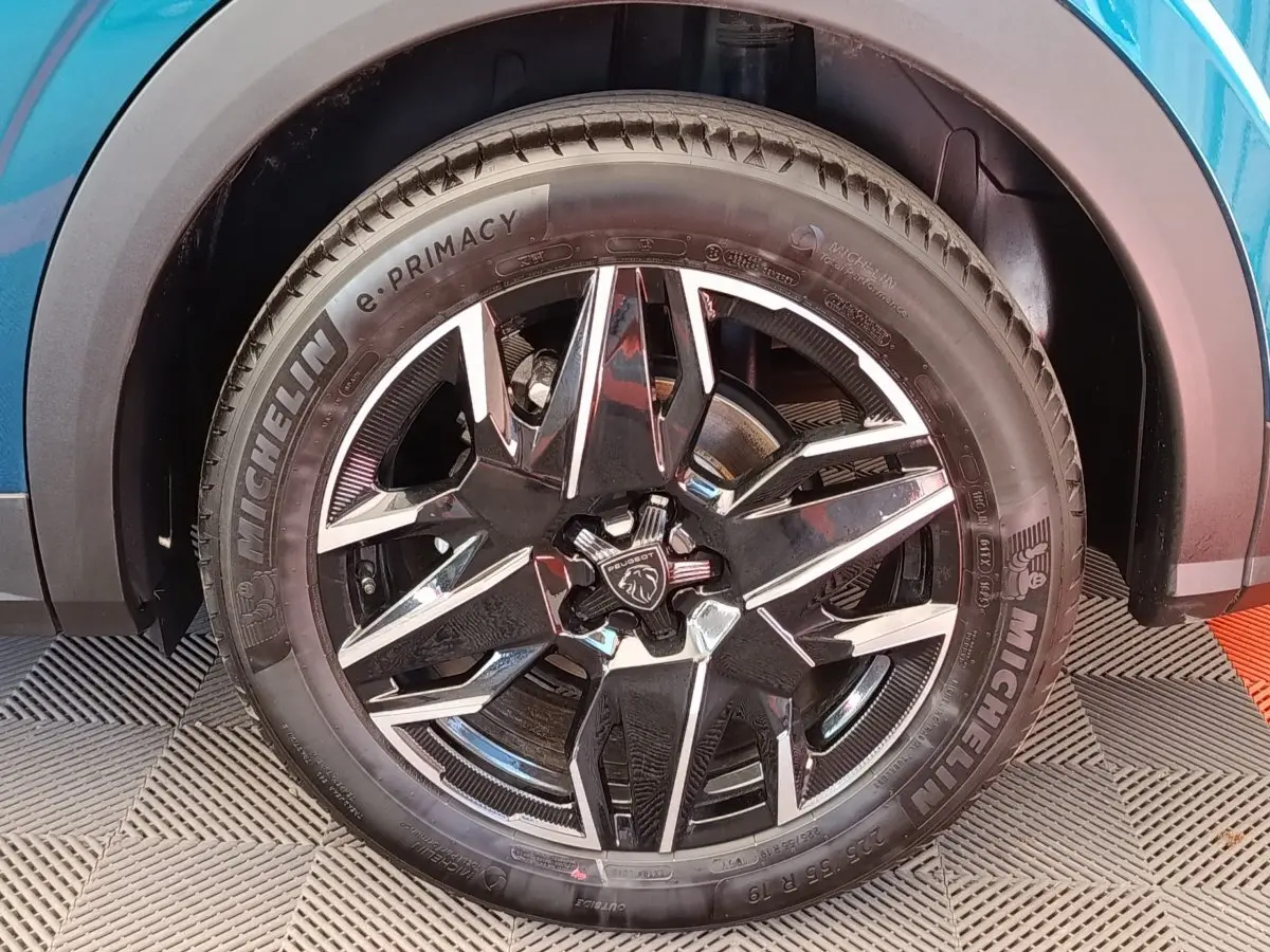 Gros plan sur la roue avant droite du Peugeot 3008 bleu, mettant en valeur la jante noire et argentée au design moderne.