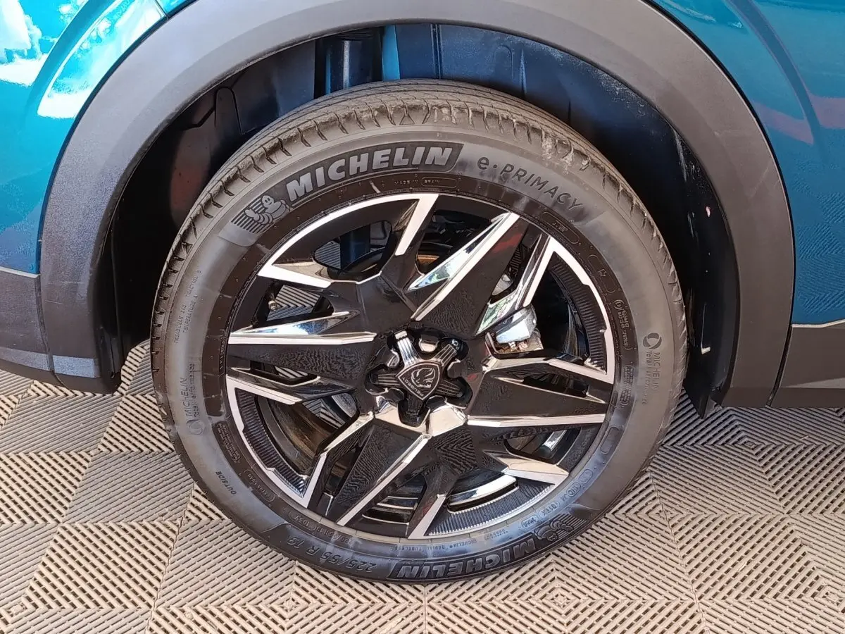 Gros plan sur la roue avant droite d’un Peugeot 3008 bleu, jante alliage noire et argent avec pneu Michelin.