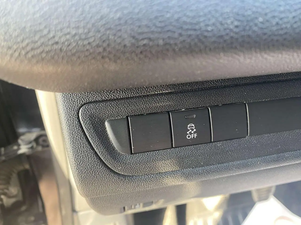 Gros plan sur le bouton de désactivation de l'ESP dans l'habitacle d'une Peugeot 208 noire.