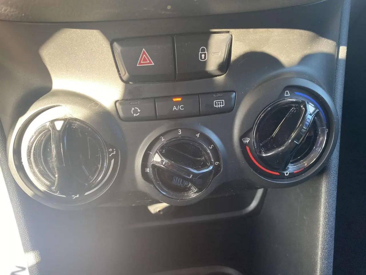 Vue rapprochée des commandes de climatisation et verrouillage central sur Peugeot 208 noire, version 2016.