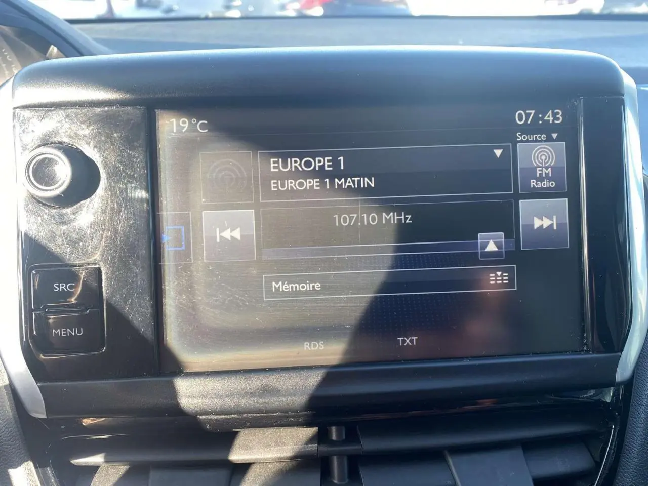 Écran tactile central de la Peugeot 208 noir, affichant la radio Europe 1 à 07:43, avec commandes autour.