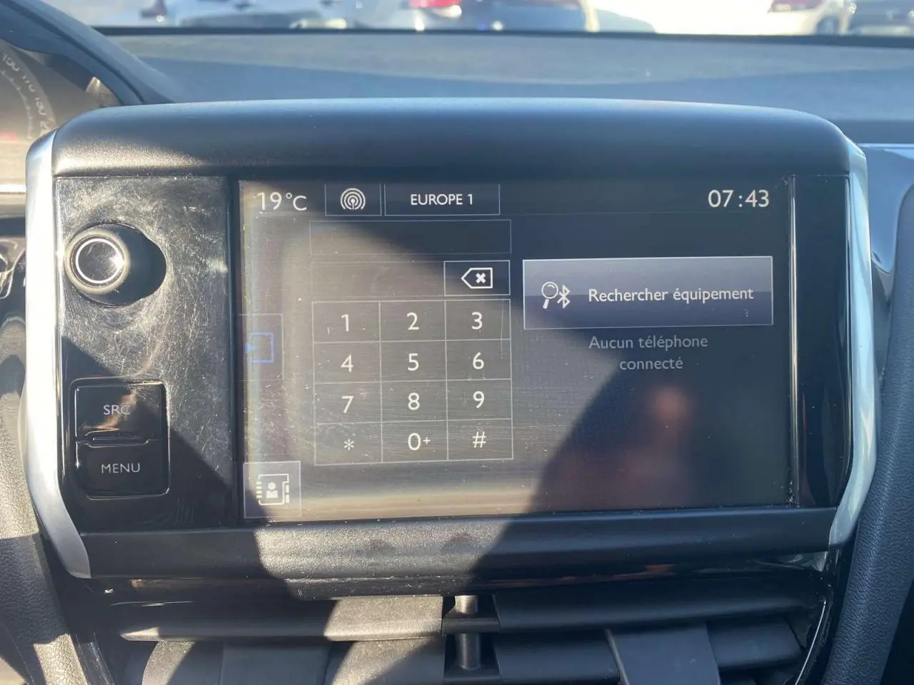 Écran tactile central de la Peugeot 208 noire montrant le menu Bluetooth avec clavier numérique, vue intérieure frontale.