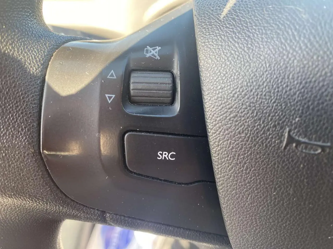 Gros plan sur les commandes audio au volant côté gauche d'une Peugeot 208 noire, version 2016.