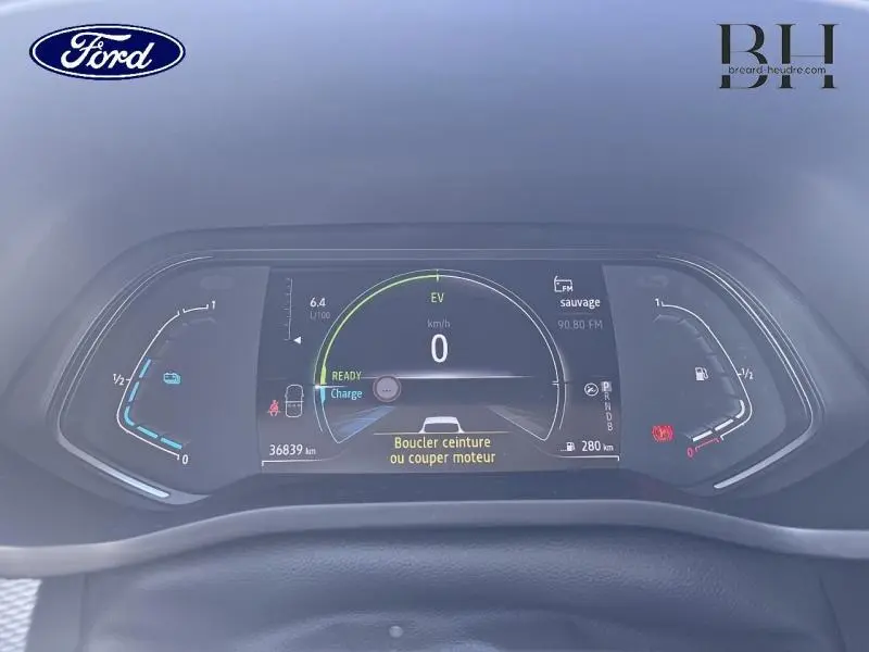 Tableau de bord numérique d'un Renault Arkana blanc perle, affichant la vitesse à 0 km/h et alertes de sécurité.