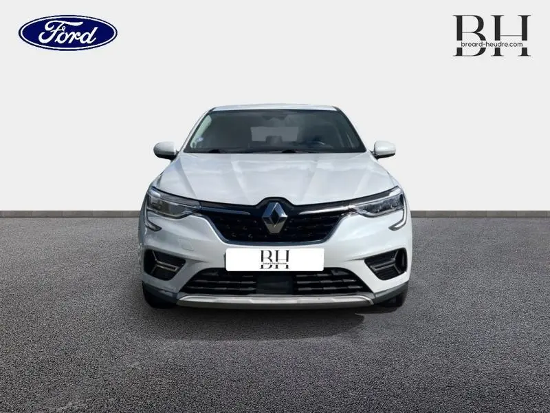 Vue frontale d'une Renault Arkana blanc perle avec calandre noire et phares LED allumés.