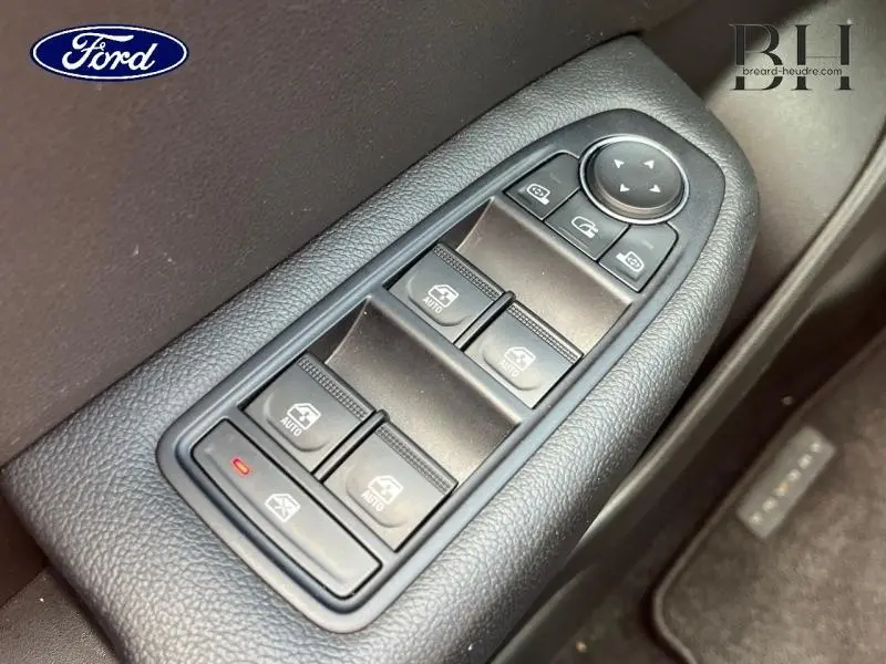 Panneau de commandes des vitres électriques côté conducteur en plastique noir, vue en plongée rapprochée.