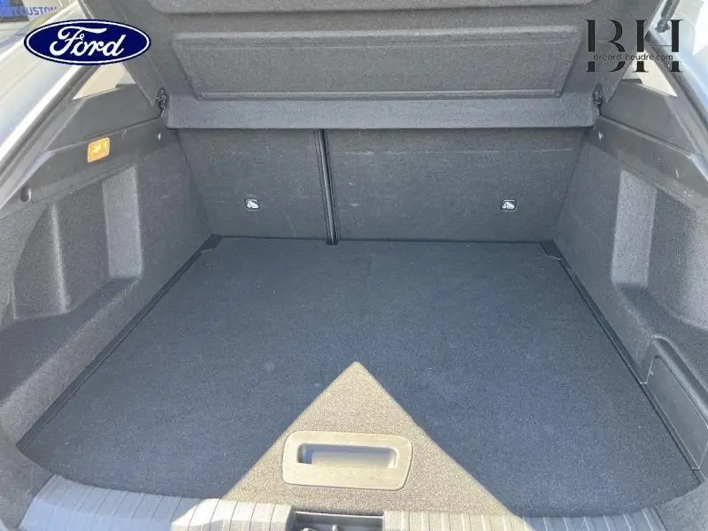 Coffre ouvert vu de l'arrière d'un Renault Arkana blanc perle, espace de chargement vide et tapis noir.