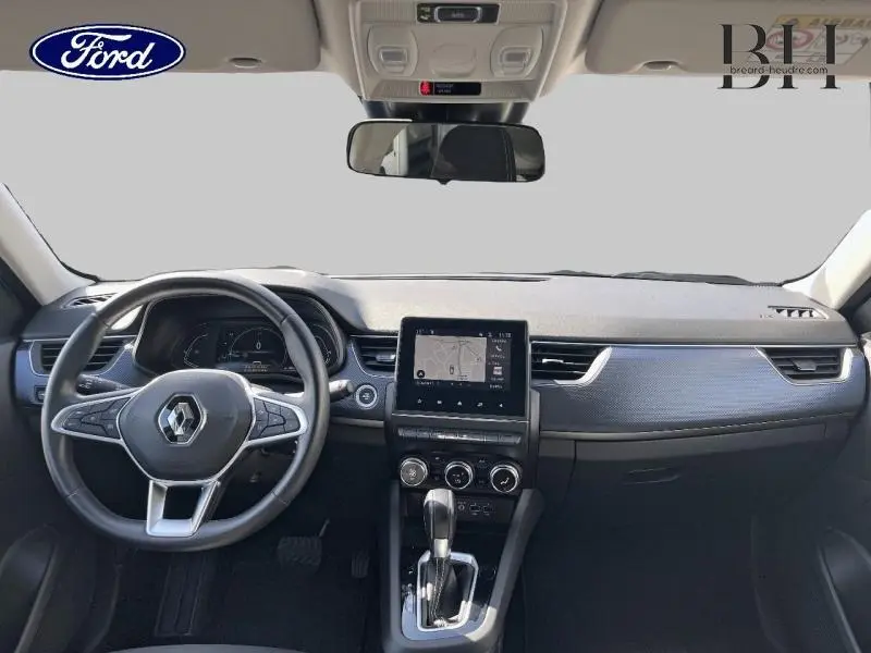 Vue intérieure avant du Renault Arkana 1.6 E-Tech blanc perle, tableau de bord avec écran tactile et volant multifonction.