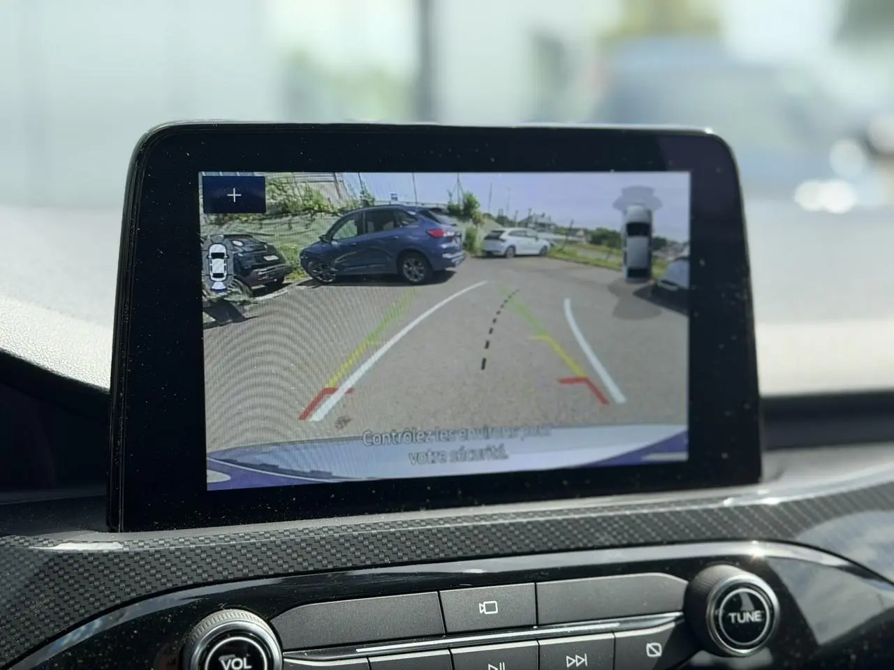 Écran tactile intérieur montrant la caméra de recul avec vue arrière d’un Ford Kuga gris Solar en stationnement.