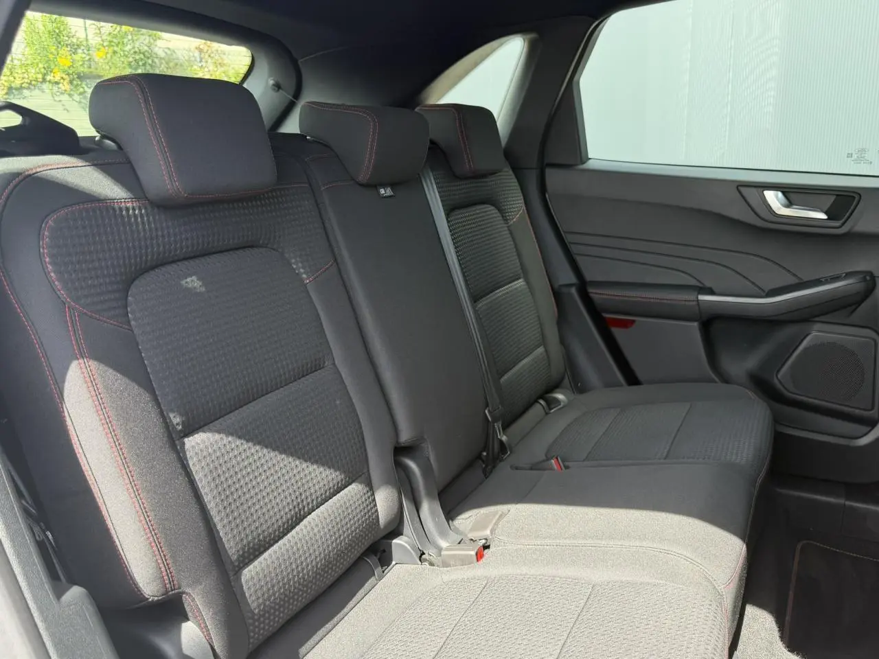 Vue intérieure côté droit des sièges arrière noirs avec surpiqûres rouges du Ford Kuga 2023 finition ST-Line.