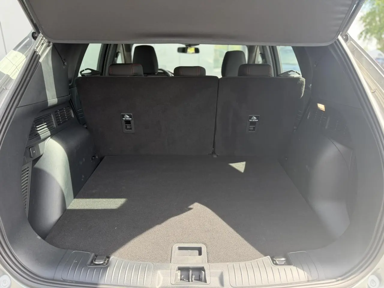 Coffre ouvert vu de l'arrière du Ford Kuga gris Solar, montrant l'espace de chargement et les dossiers des sièges arrière.
