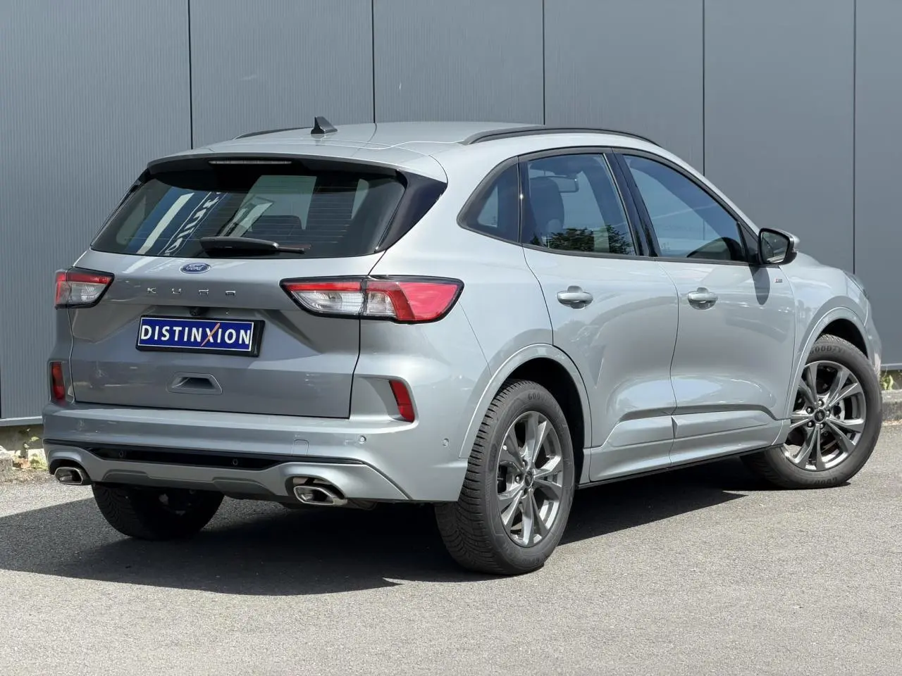 Vue 3/4 arrière droite du Ford Kuga gris Solar 2023 avec double sortie d’échappement et jantes alliage 18 pouces.