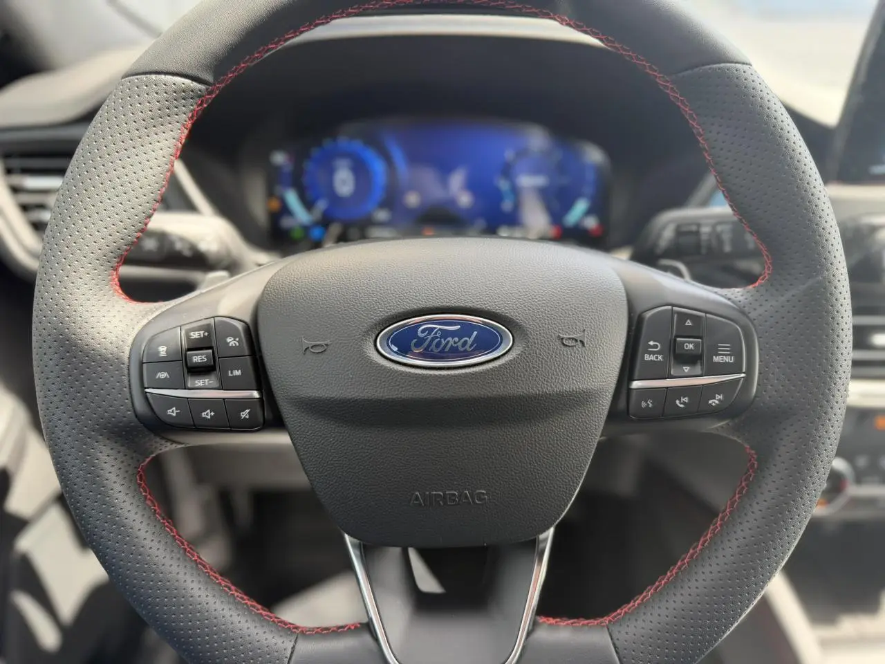 Volant perforé avec surpiqûres rouges du Ford Kuga 2.0 EcoBlue 120 BVA ST-Line, vue frontale intérieure.