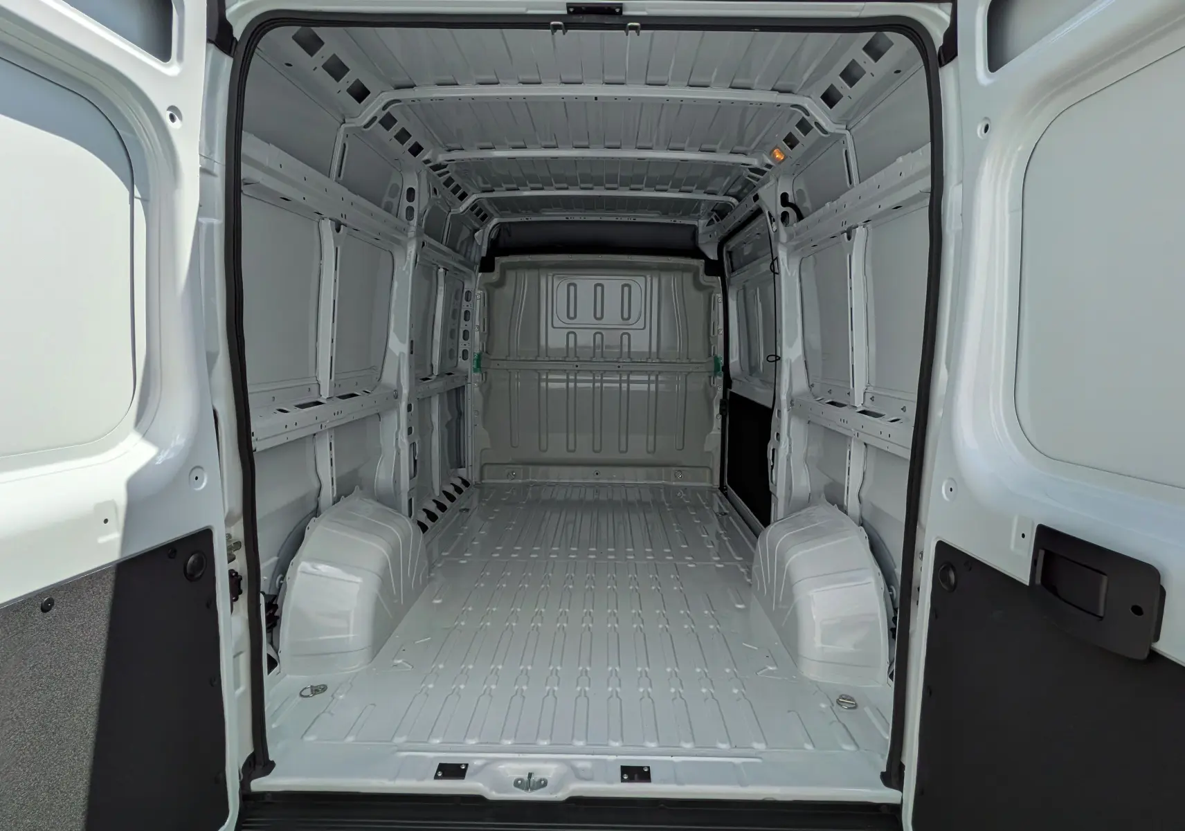 Vue intérieure arrière du fourgon blanc FIAT Ducato 2026, espace de chargement vide et métallique, sans aménagement.