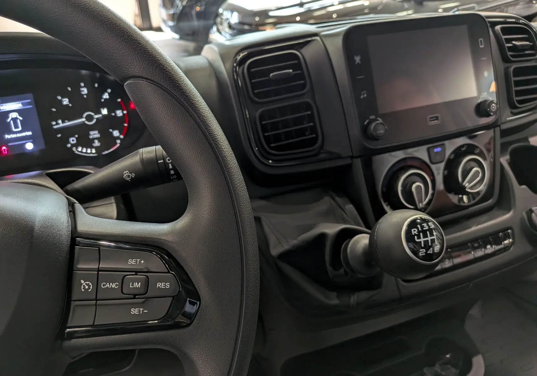 Vue intérieure rapprochée du tableau de bord et levier de vitesse manuel du Fiat Ducato Fourgon blanc, avec commandes au volant visibles.