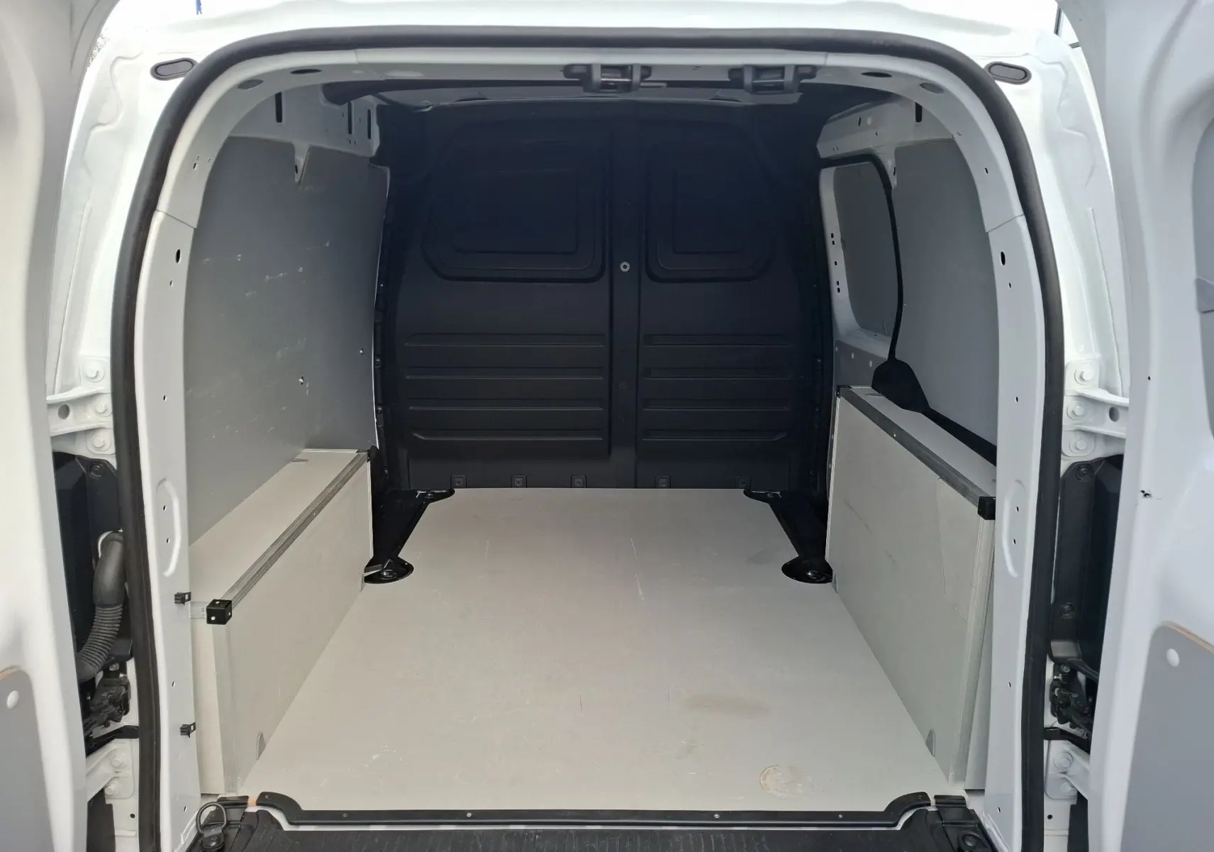 Vue arrière ouverte du Renault Kangoo Pro blanc montrant l'espace de chargement vide et les parois latérales grises.
