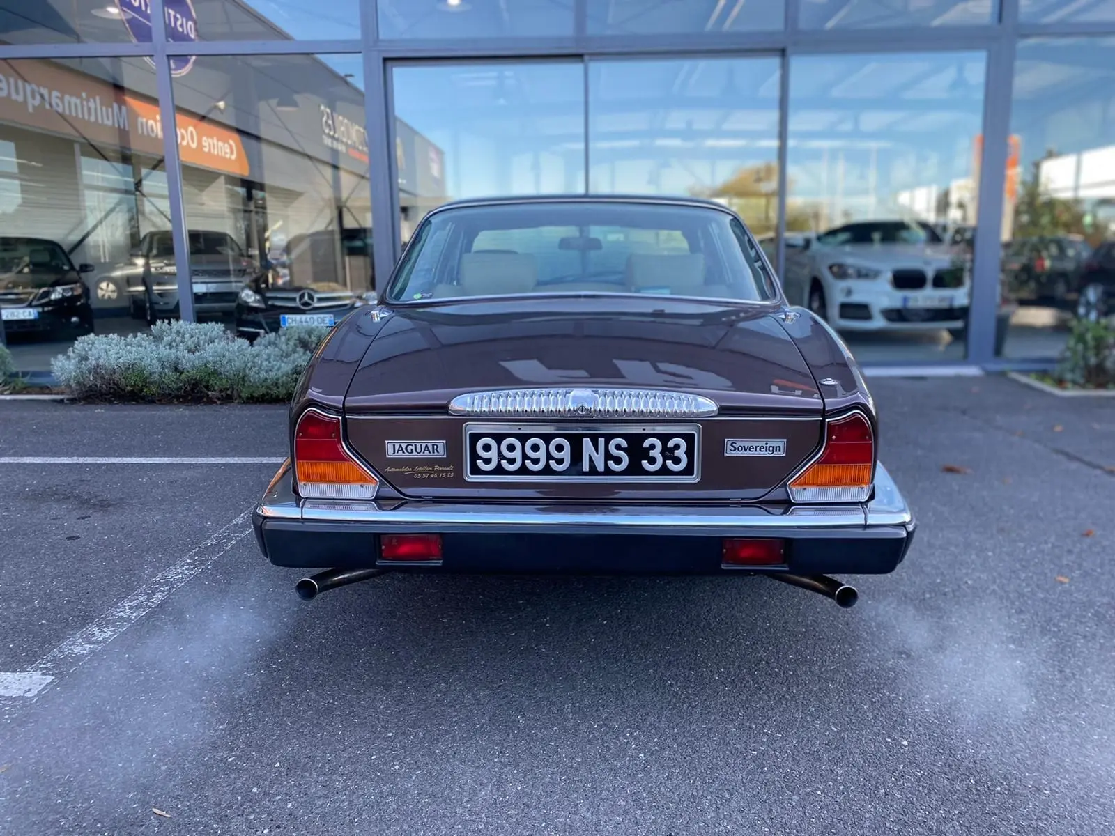 Vue arrière d'une Jaguar XJ6 Série 3 4.2 Sovereign marron de 1985 avec double sortie d'échappement fumante.