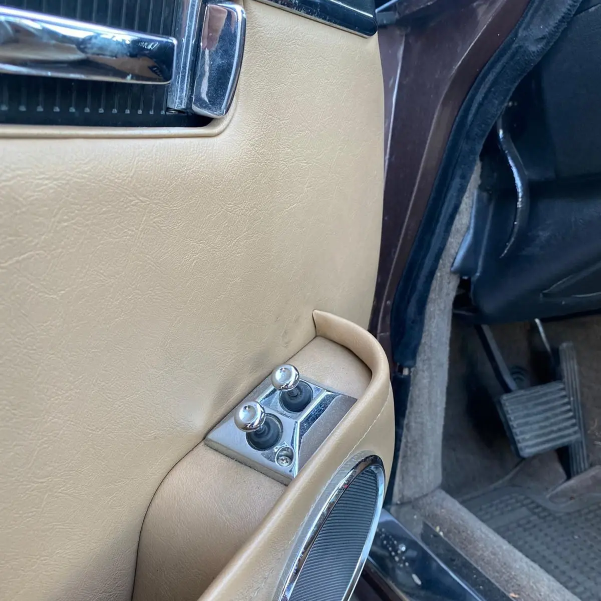 Gros plan sur la portière côté gauche marron d'une Jaguar XJ6 Série 3 4.2 Sovereign de 1985 avec commandes chromées.