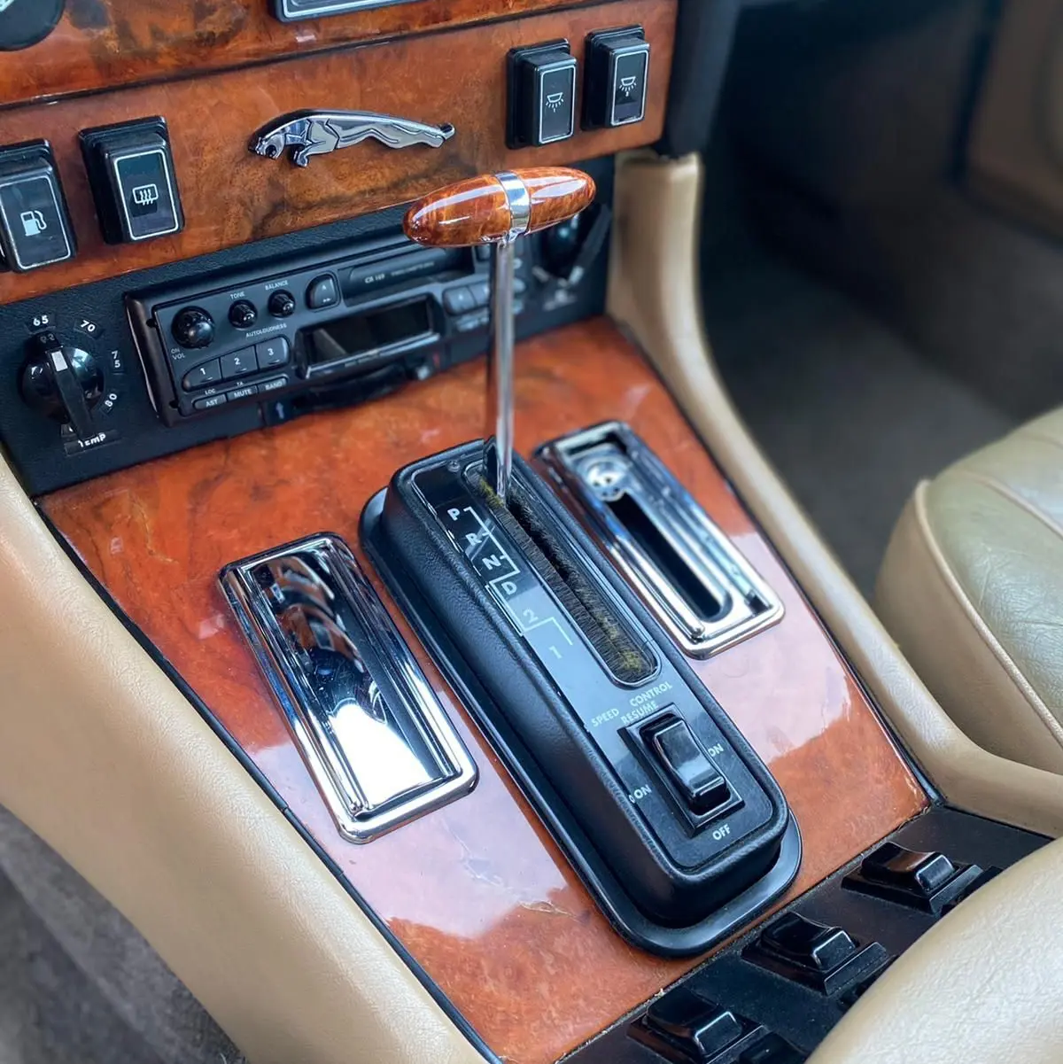 Gros plan sur la console centrale en bois marron de la Jaguar XJ6 Série 3 4.2 Sovereign de 1985 avec levier de vitesses automatique.