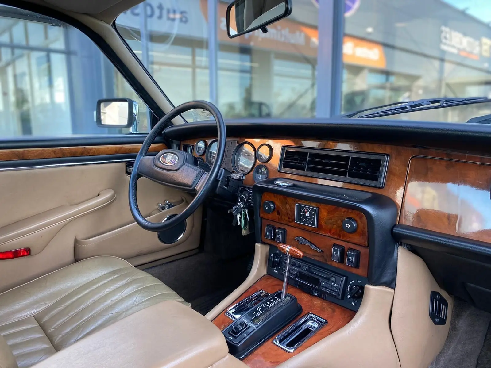Intérieur beige et bois d'une Jaguar XJ6 Série 3 4.2 Sovereign 1985, vue côté conducteur sur tableau de bord classique.