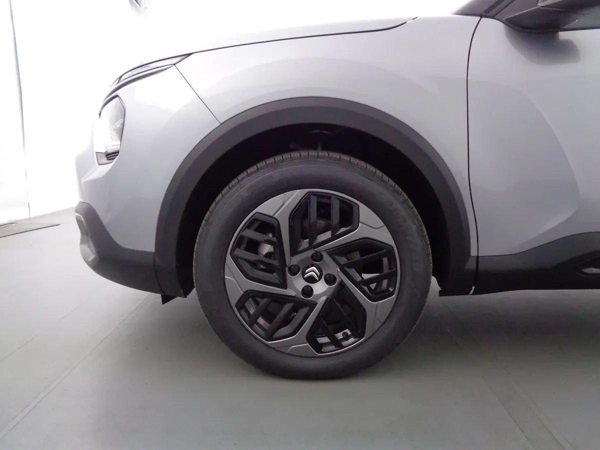 Gros plan sur la roue avant gauche d'une Citroën C4 gris Artense métal avec jante alliage bicolore au design moderne.