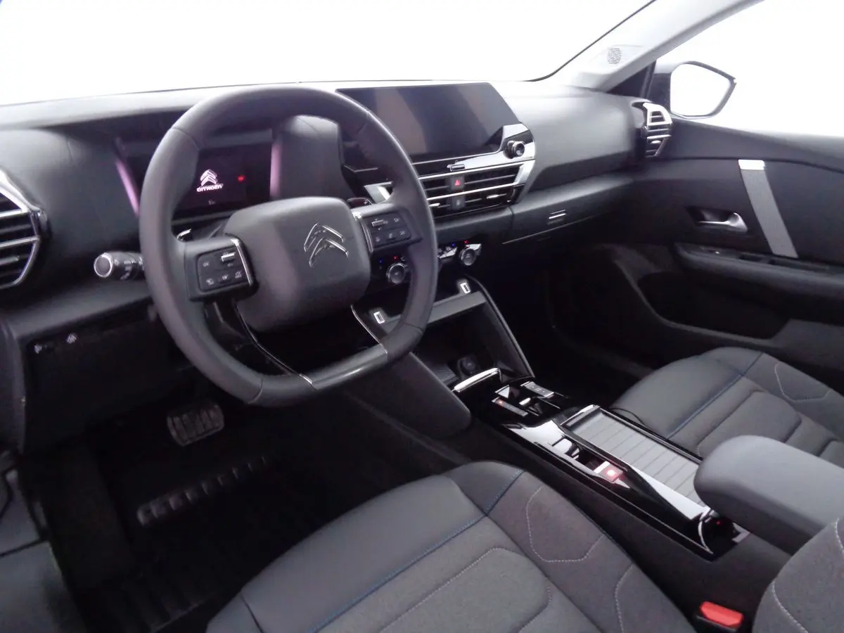 Vue intérieure côté conducteur de la Citroën C4 2023 avec tableau de bord noir et volant multifonction.