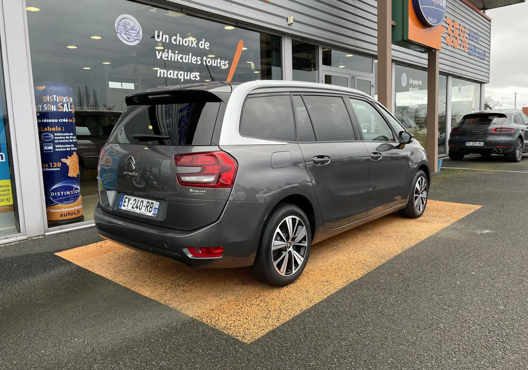Vue 3/4 arrière droite d'un Citroën Grand C4 Picasso gris 2018, avec feux arrière distinctifs et toit blanc contrastant.