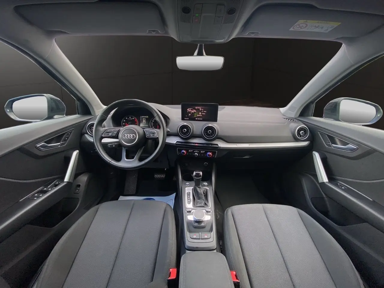 Intérieur noir de l'Audi Q2 2023 vu de face, avec tableau de bord moderne et écran central tactile.