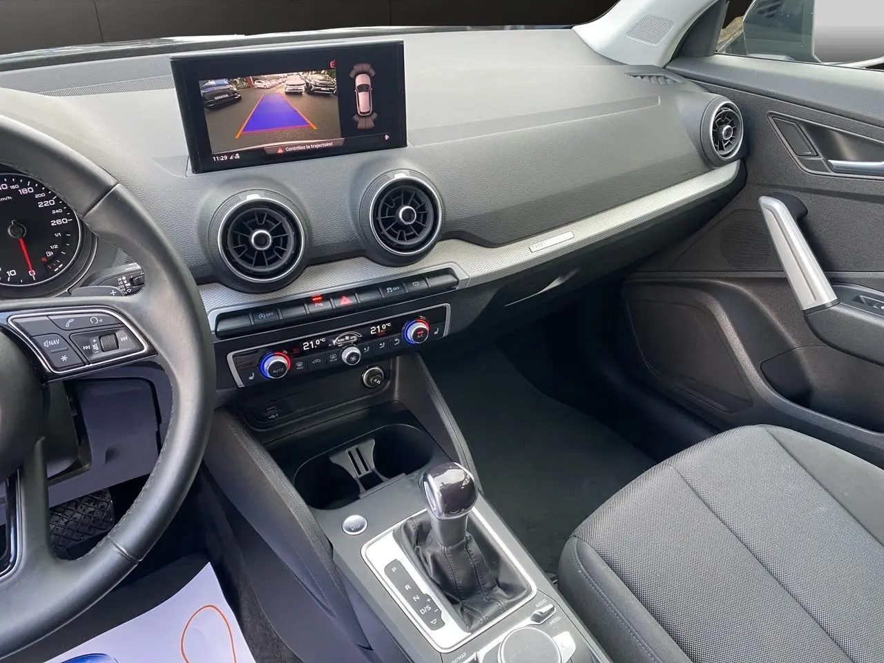 Vue intérieure côté passager de l'Audi Q2 35 TFSI S-Line 2023 avec écran caméra de recul et sellerie tissu noire.