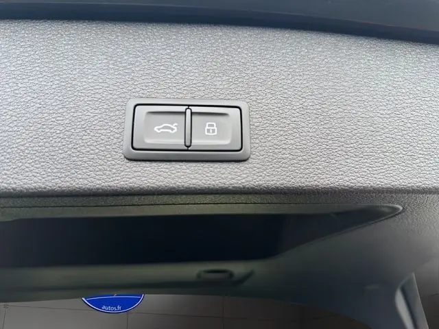 Vue rapprochée du tableau de bord de l'Audi Q2 35 TFSI 2023, avec écran central affichant l'interface smartphone et commandes de climatisation.
