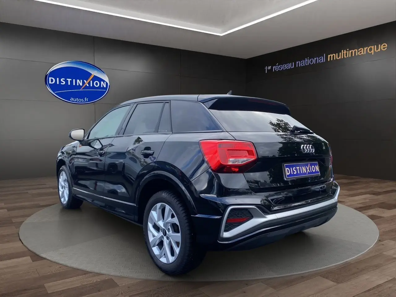 Audi Q2 noir mito vue 3/4 arrière droit, jantes alliage 17 pouces et hayon motorisé visible en showroom.