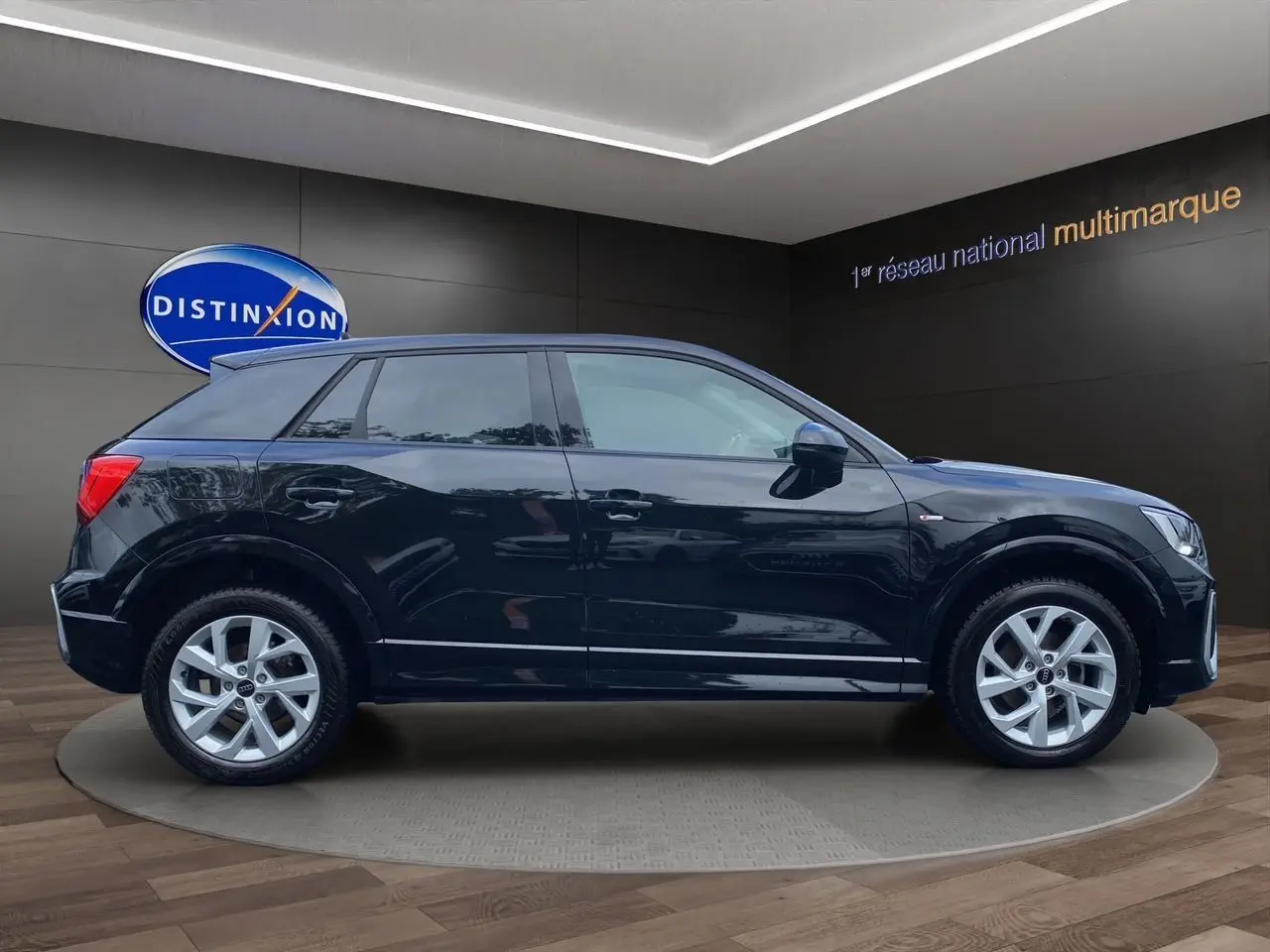 Audi Q2 noir mito vue profil côté gauche, jantes alliage 17 pouces et finition S-Line visible en showroom.