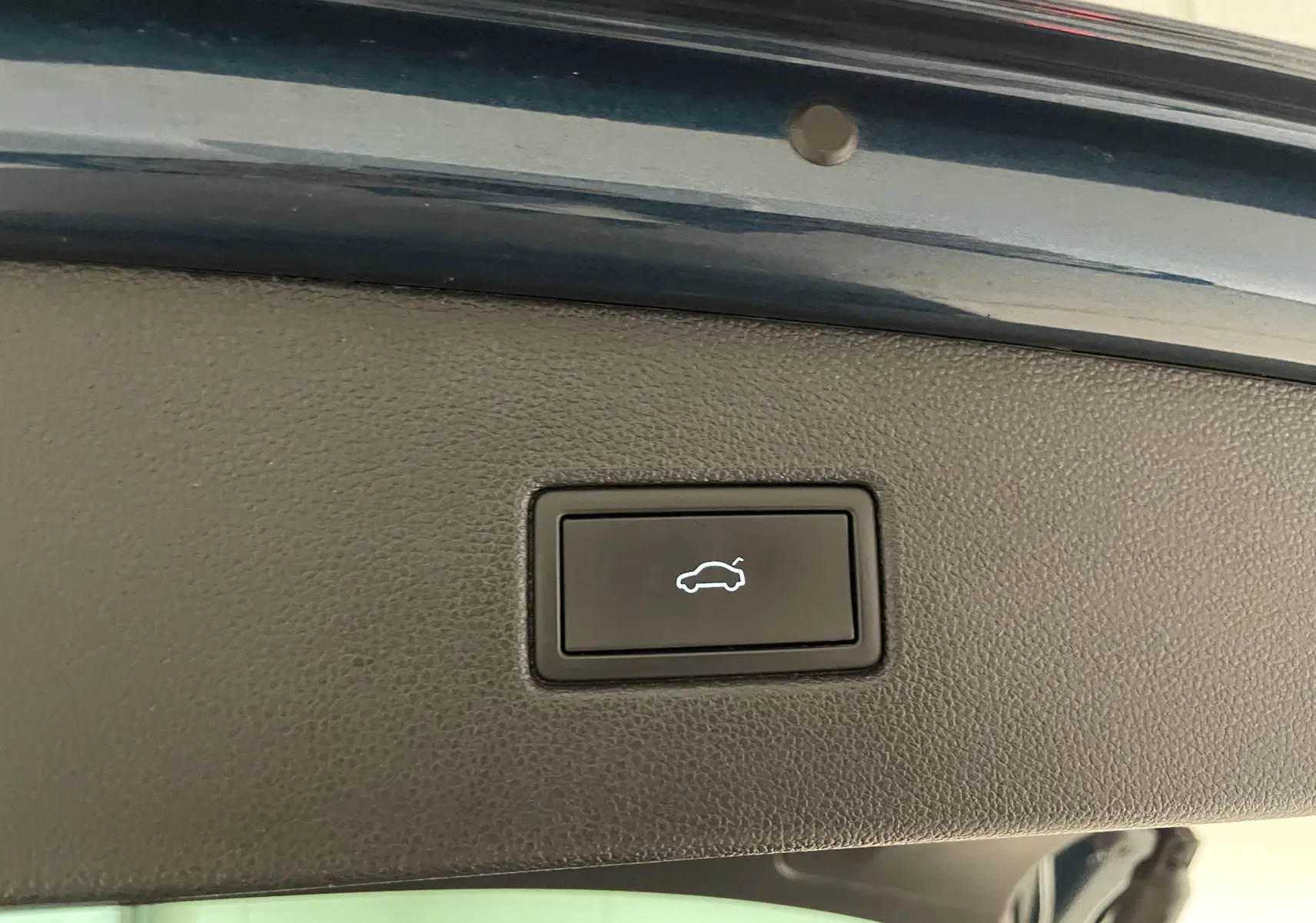 Bouton d'ouverture électrique du hayon sur la partie intérieure du coffre du Volkswagen Tiguan Nightshade Blue 2024.