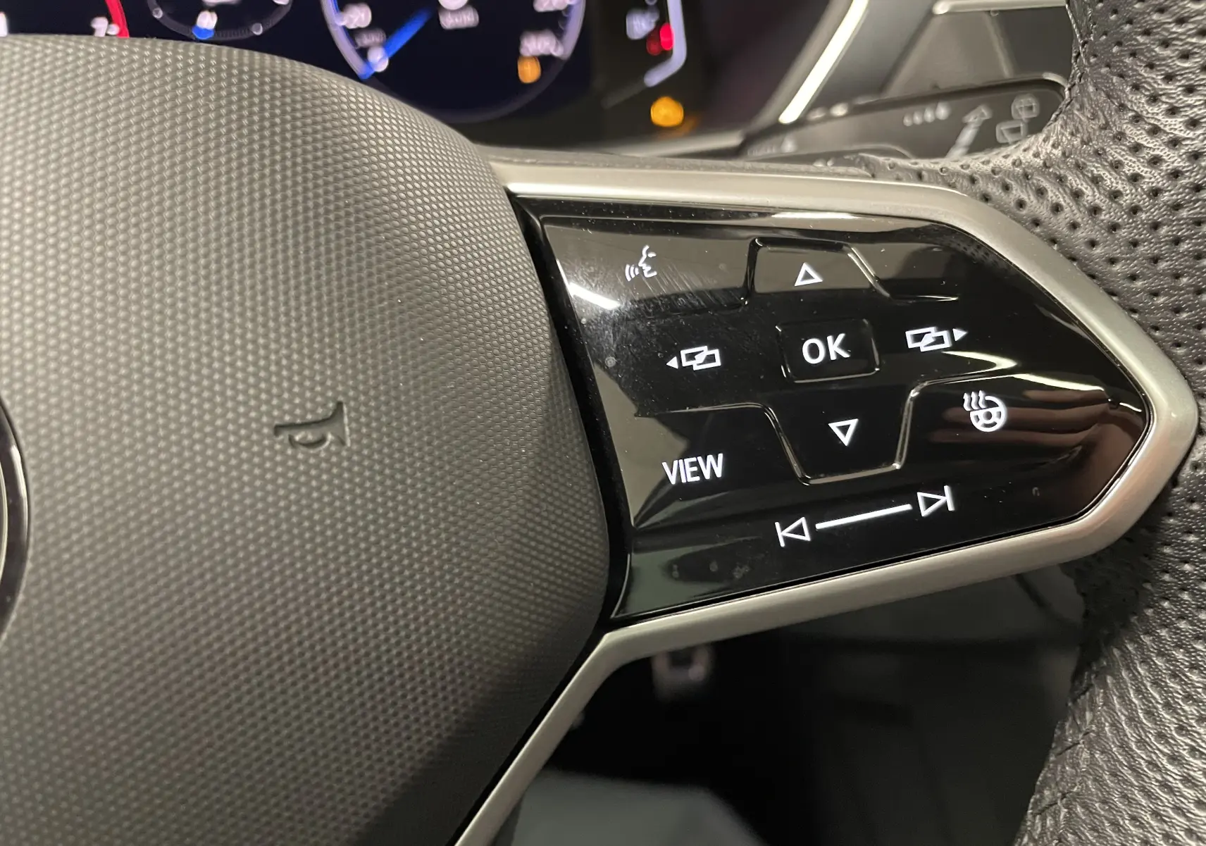 Gros plan sur les commandes du volant à droite du Volkswagen Tiguan 2024, avec tableau de bord numérique en arrière-plan.