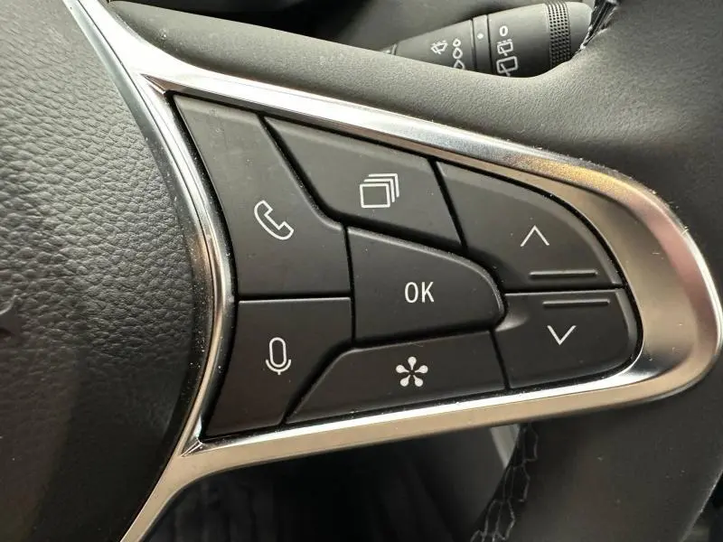 Gros plan sur les commandes multifonctions noires du volant du Renault Captur 2025, avec finition chromée autour.
