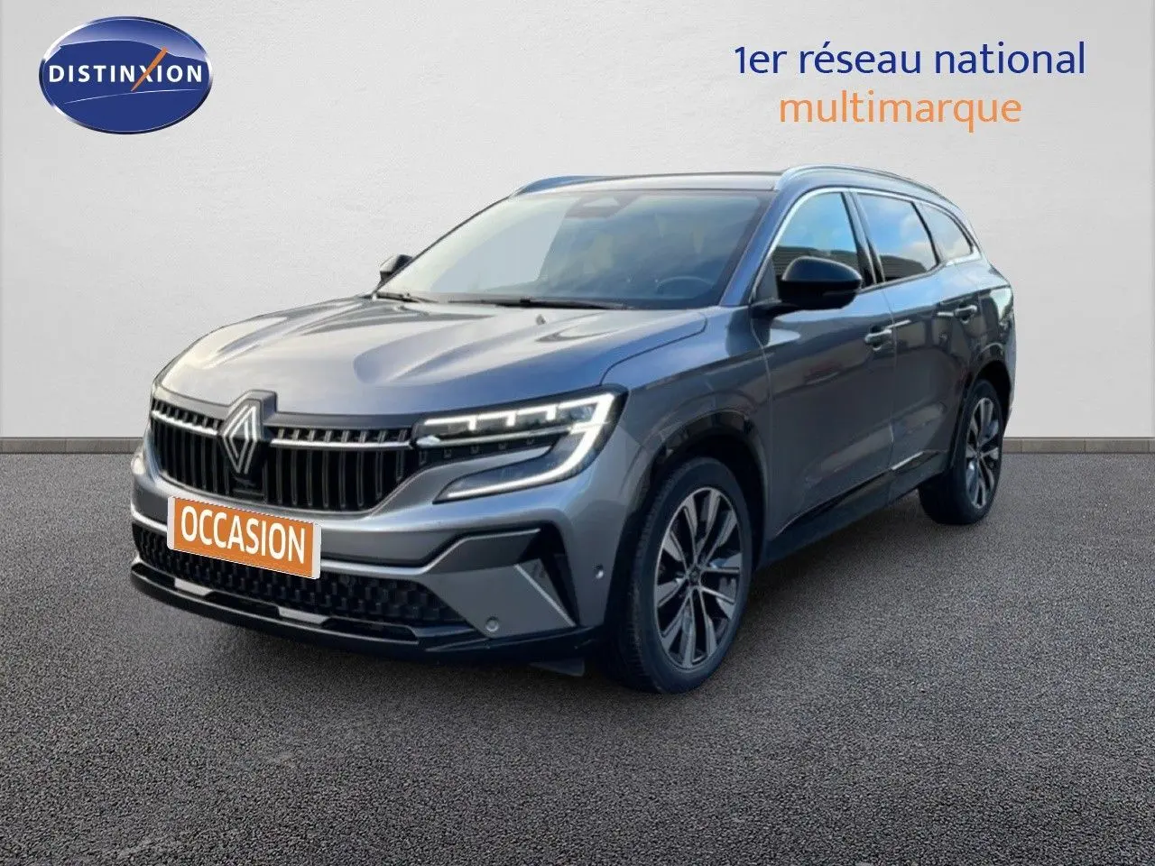 Renault Espace VI E-Tech gris schiste, vue 3/4 avant droit avec calandre distinctive et feux LED allumés.