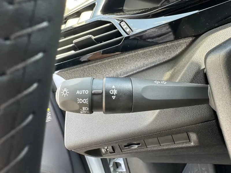 Gros plan sur la commande des phares et clignotants côté gauche du tableau de bord d'une Peugeot 308 bleu 2025.