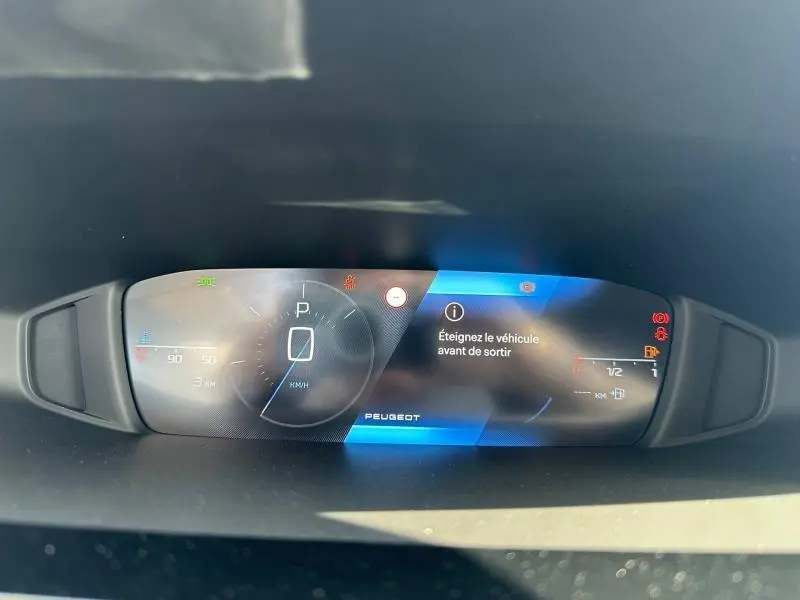Tableau de bord numérique de Peugeot 308 bleu, affichant la vitesse à 0 km/h et un message d'alerte.