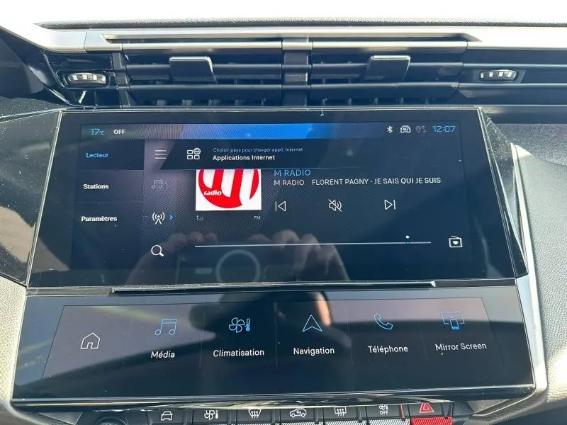 Écran tactile central du tableau de bord de la Peugeot 308 bleu, affichant la radio et les commandes multimédia.
