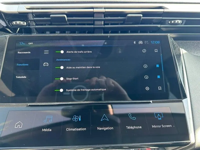 Écran tactile central du tableau de bord de la Peugeot 308 bleu, affichant les aides à la conduite et la climatisation.