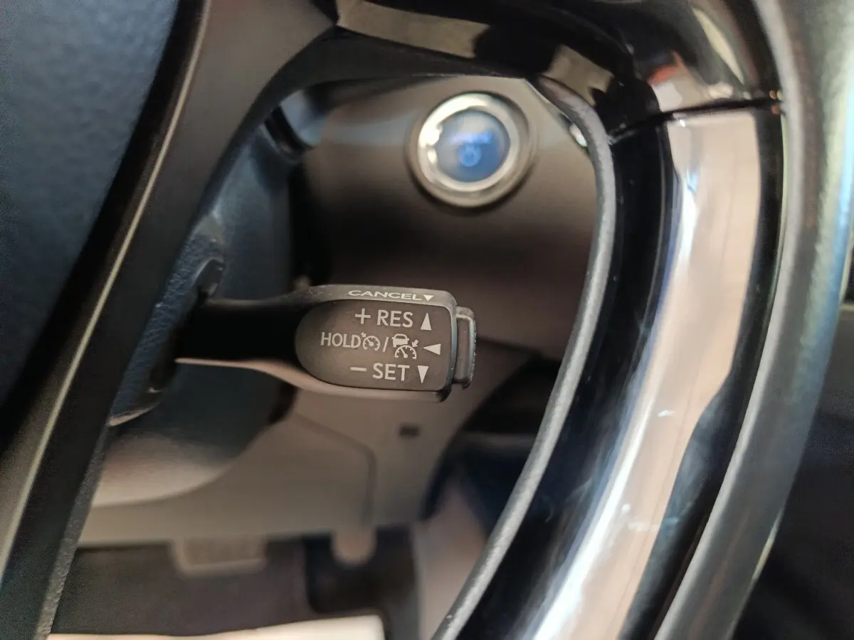 Gros plan sur la commande du régulateur de vitesse au volant d'un Toyota C-HR gris clair, intérieur noir.
