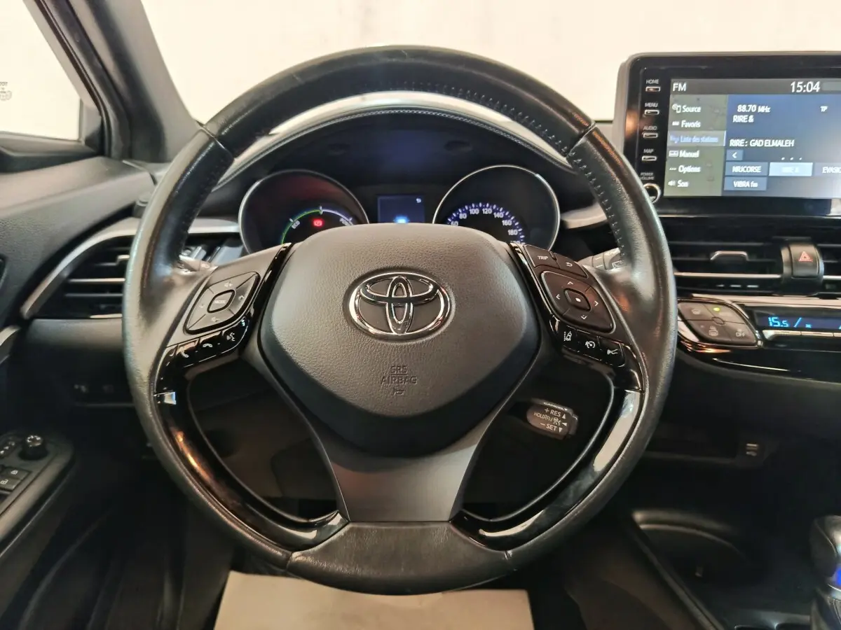 Volant cuir noir de la Toyota C-HR 2.0 Hybride 2022 avec commandes intégrées et tableau de bord numérique.