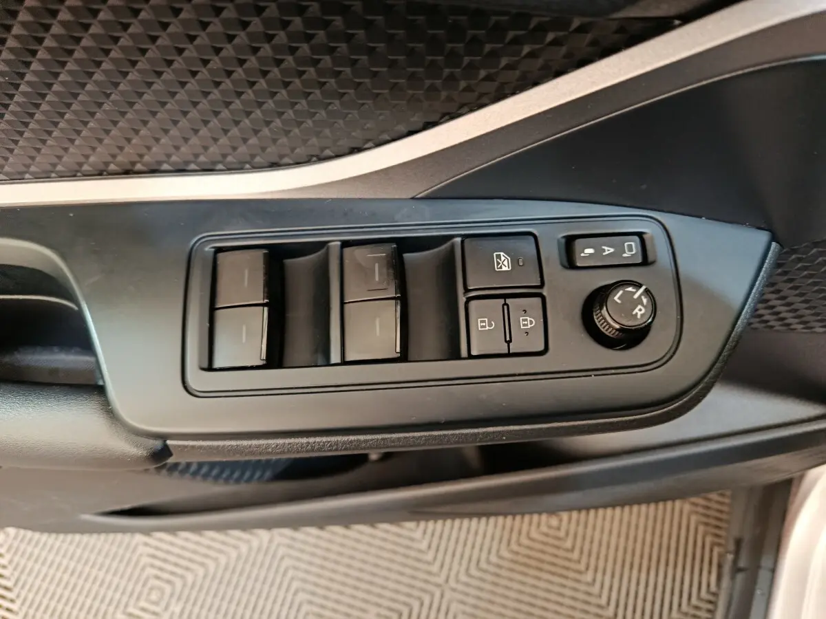 Gros plan sur les commandes de lève-vitres et réglage des rétroviseurs côté conducteur du Toyota C-HR gris clair.