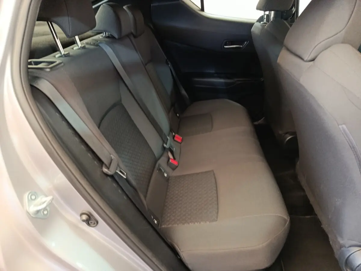 Vue intérieure côté gauche sur la banquette arrière grise du Toyota C-HR 2.0 Hybride 2022 avec ceintures et appuie-têtes visibles.