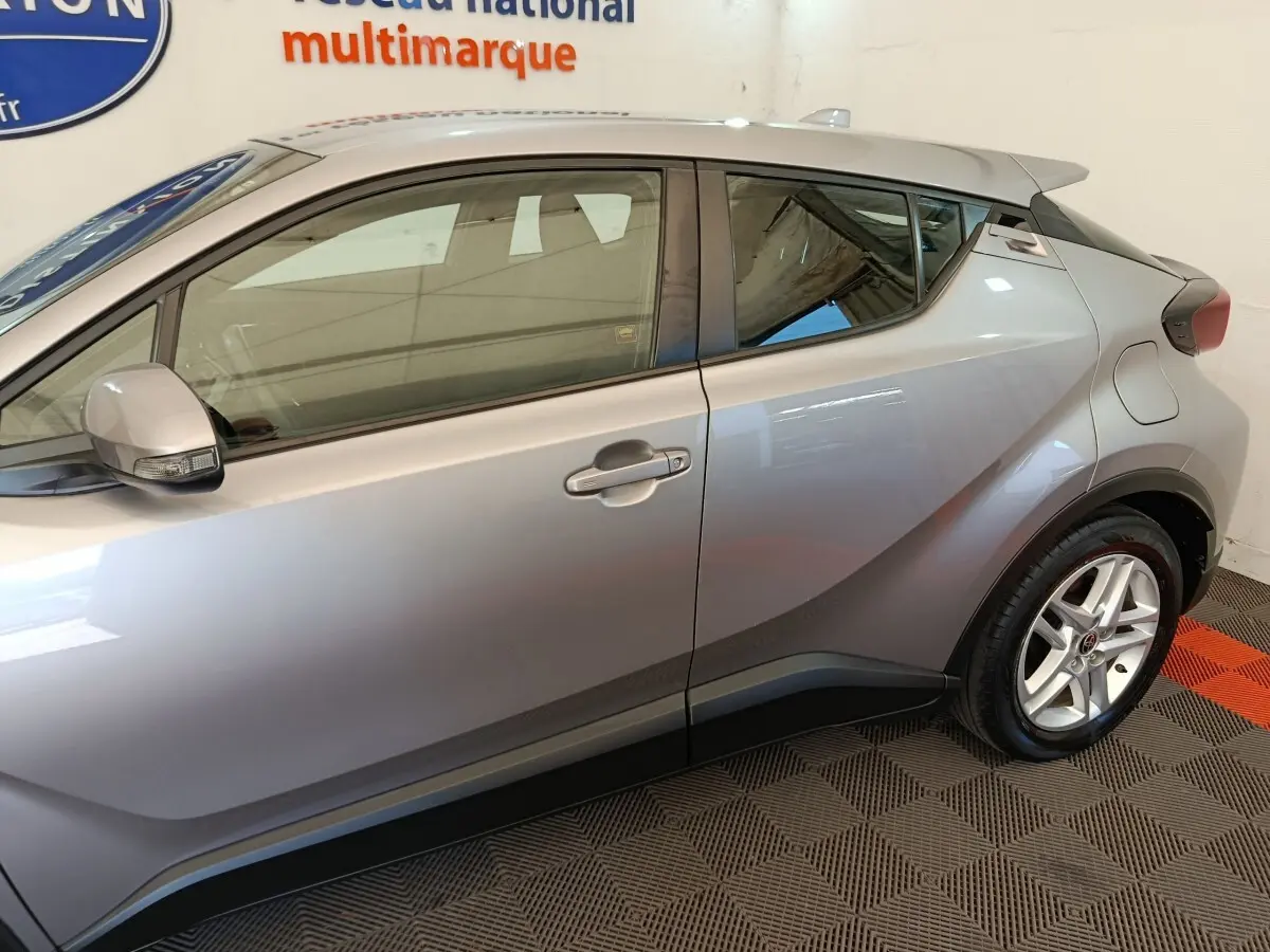 Vue latérale droite d'un Toyota C-HR gris clair 2022, mettant en valeur ses lignes anguleuses et la jante alliage.