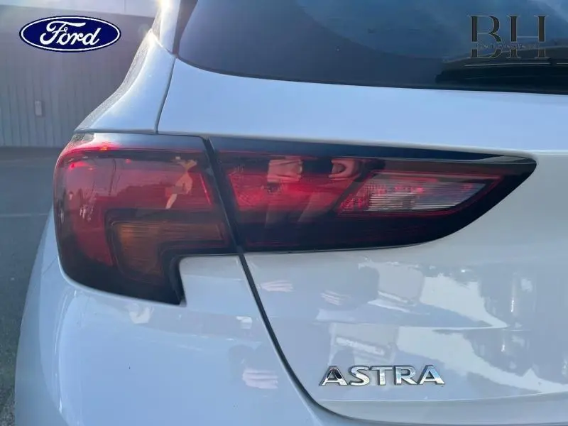 Gros plan sur le feu arrière gauche blanc glacier d'une Opel Astra 2020 avec logo et badge visibles.
