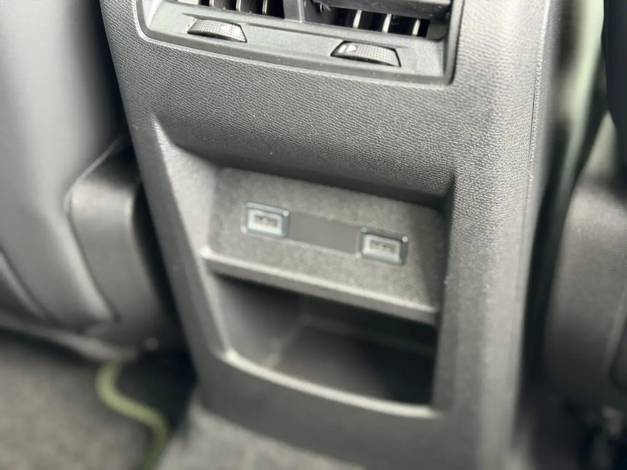 Vue rapprochée des ports USB arrière et rangement central en plastique noir dans l’habitacle de la Peugeot 308 gris Artense.