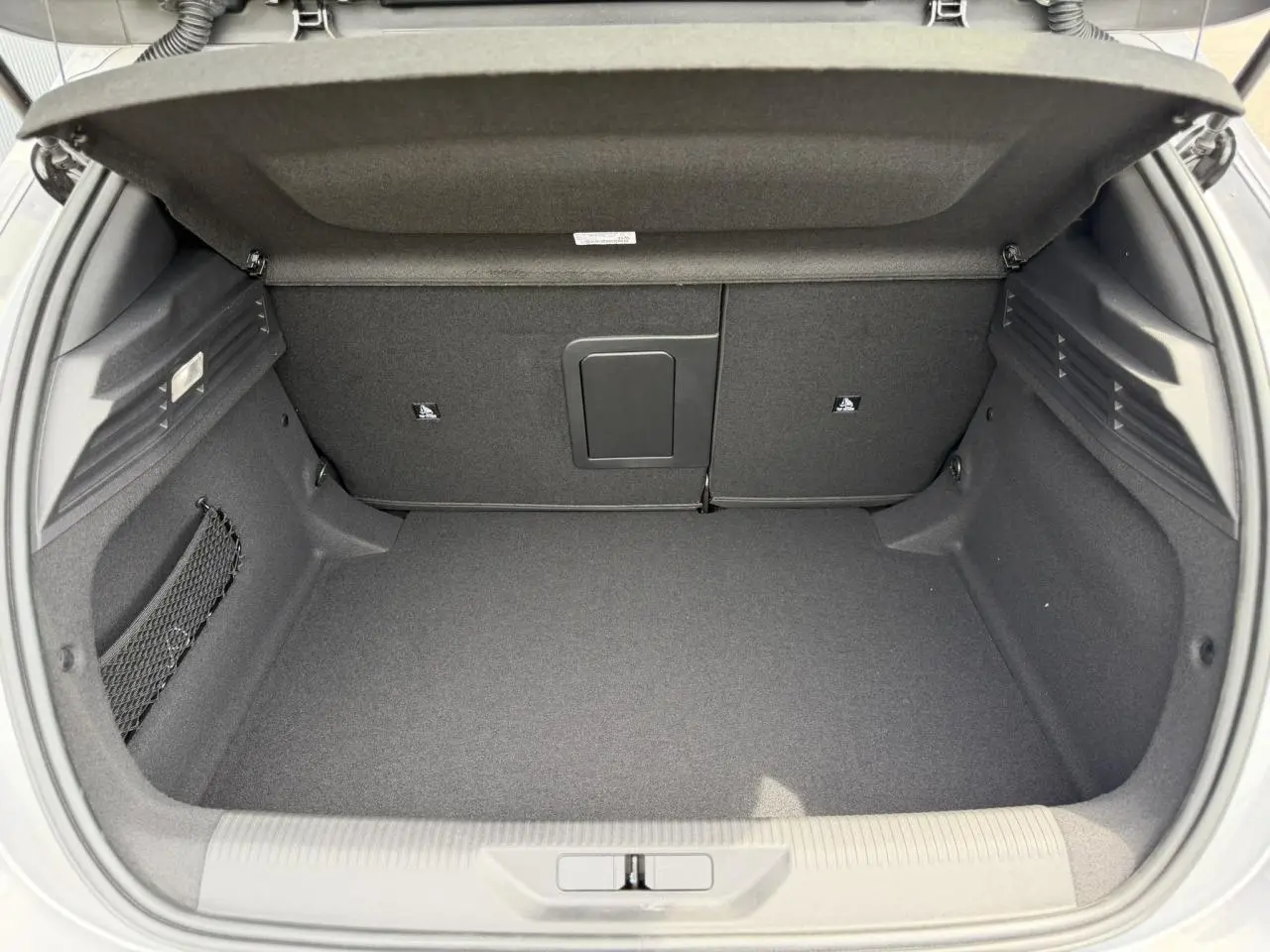 Coffre ouvert vu de l'arrière d'une Peugeot 308 gris Artense, intérieur spacieux et revêtement noir.